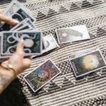 Hands dealing tarot cards for a reading on a stylish geometric rug.